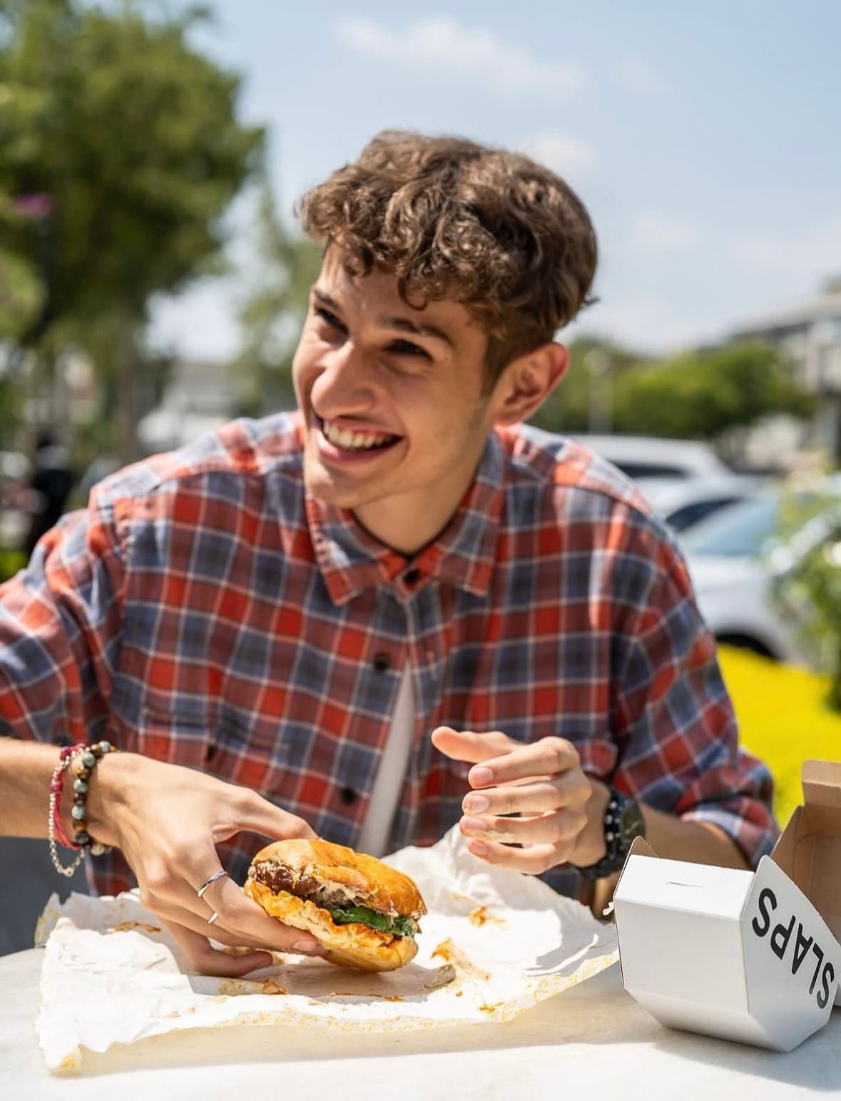 A customer enjoying a SLAPS burger at an outdoor table