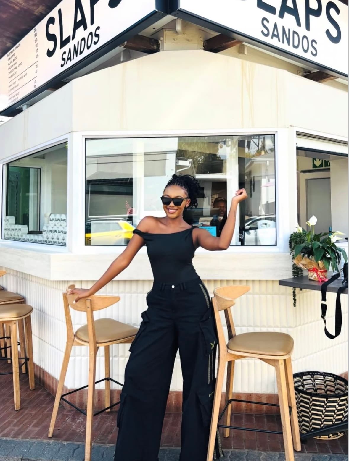 A customer posing in front of the SLAPS Sandos storefront