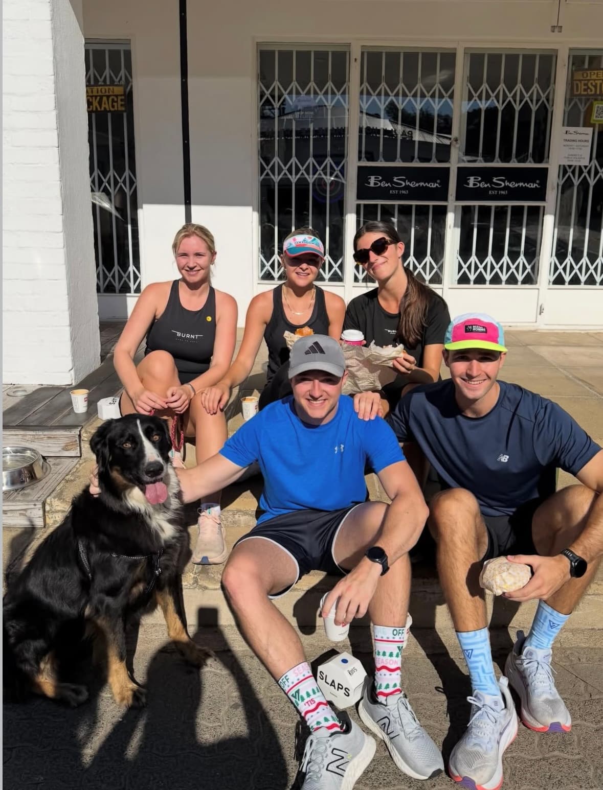 A run club group with their dog stopped outside SLAPS Sandos