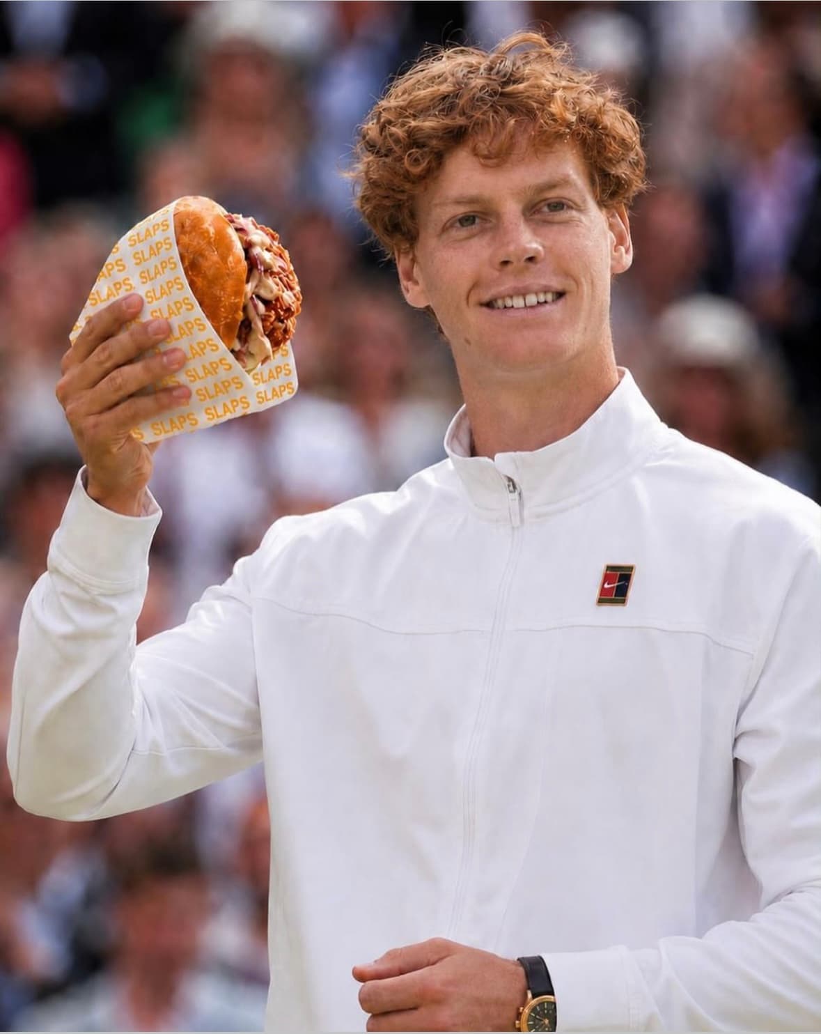 A tennis player holding a SLAPS sando courtside