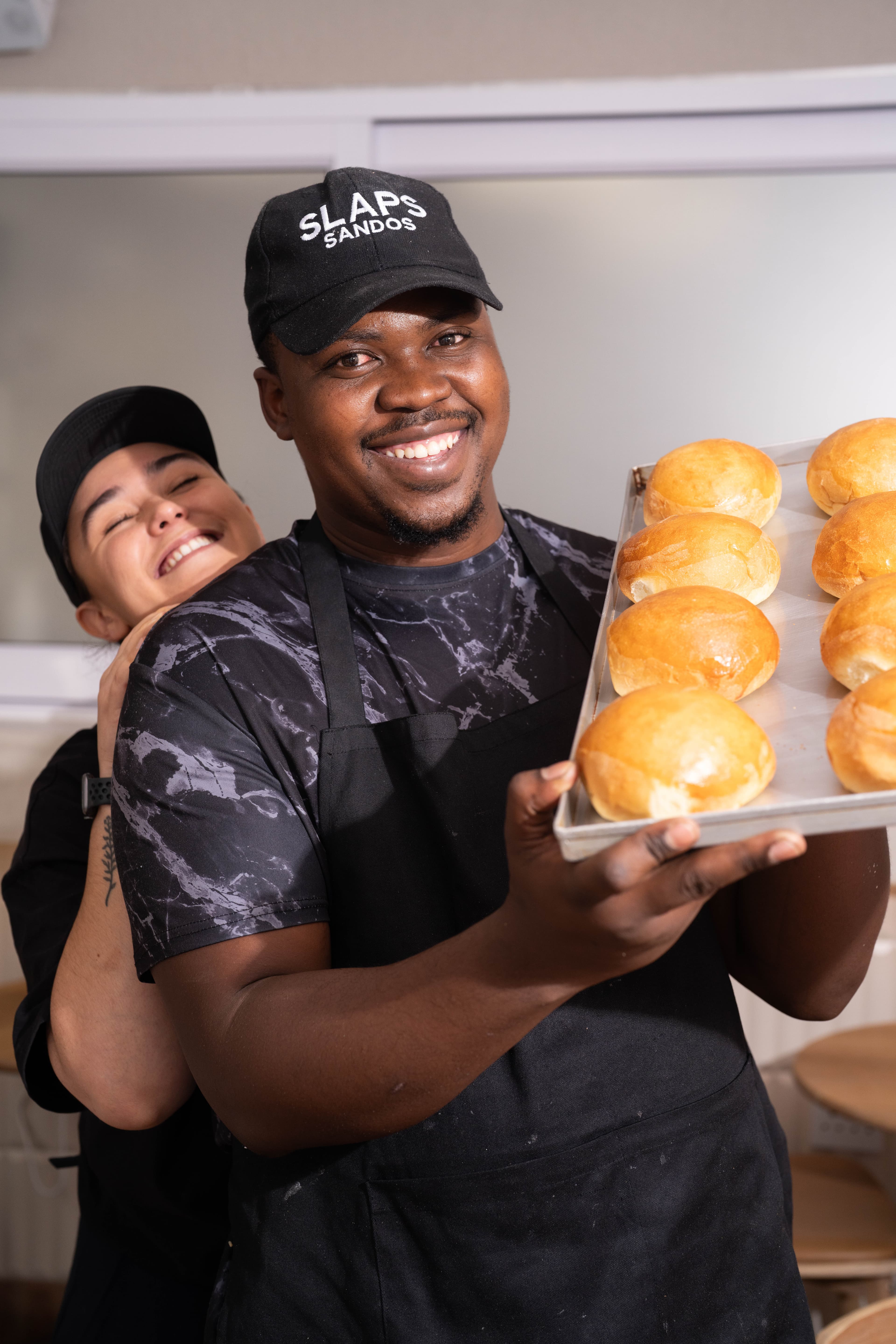 The SLAPS Sandos team laughing while prepping buns